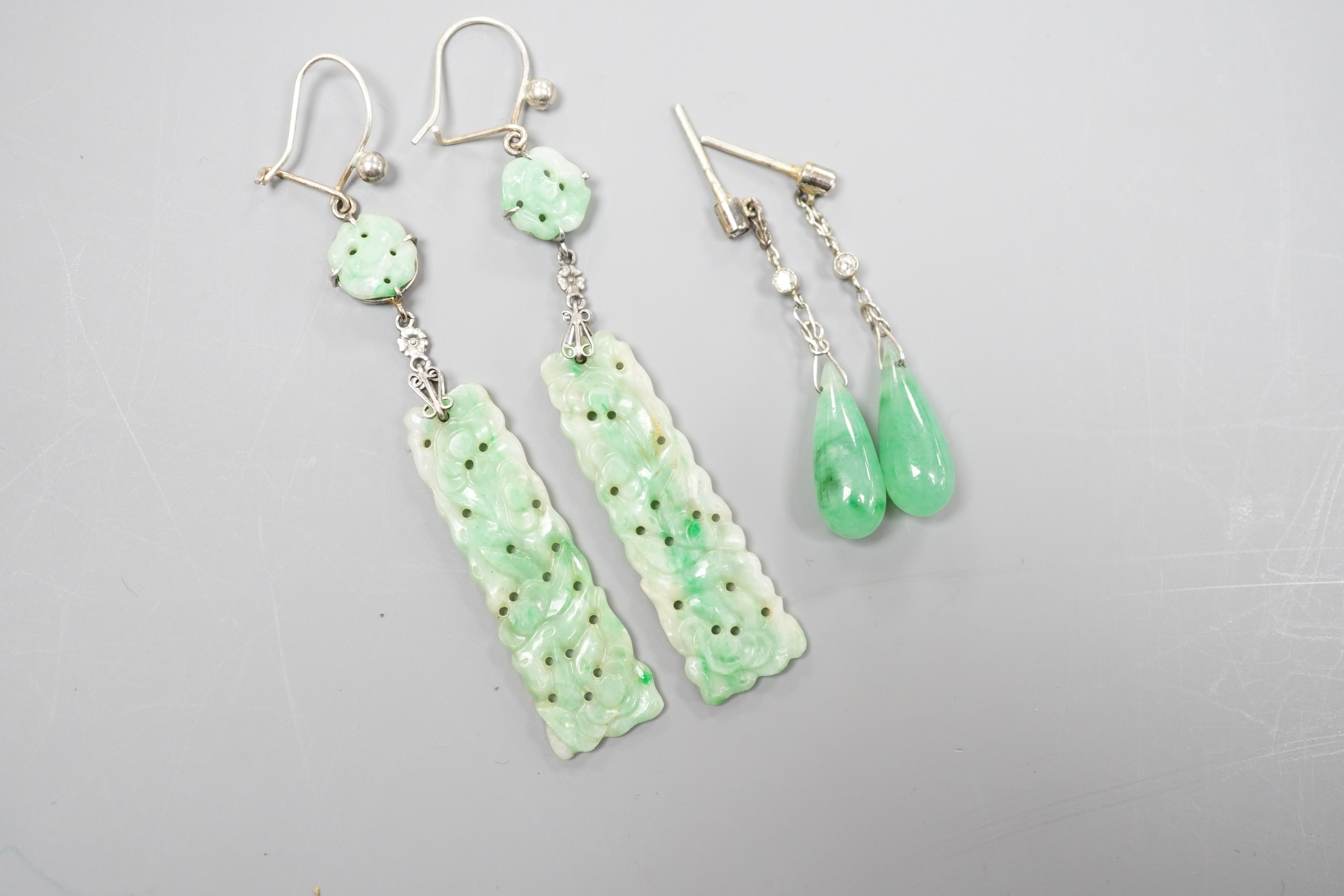 A pair of white metal pair shaped jade and two stone diamond set drop earrings, 37mm and one other pair of carved jade drop earrings, gross weight 8 grams.